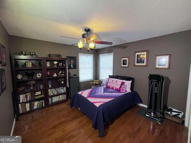 bedroom featuring ceiling fan, a textured ceiling, and dark hardwood / wood-style flooring