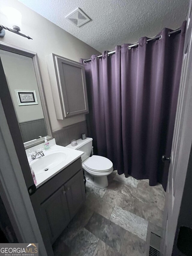 bathroom featuring vanity, tile patterned flooring, toilet, and a textured ceiling