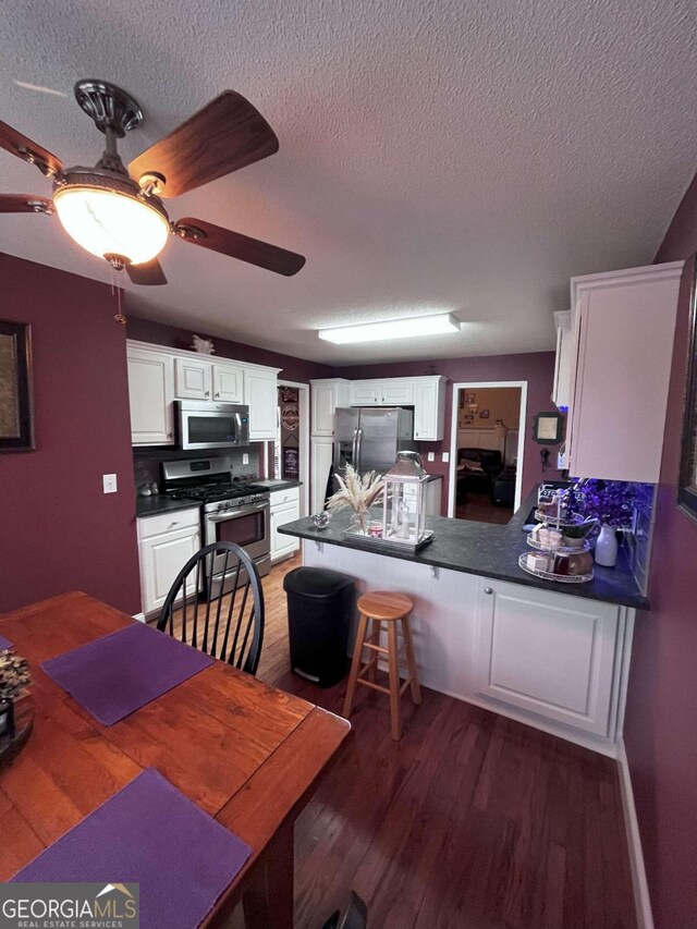 kitchen featuring appliances with stainless steel finishes, dark hardwood / wood-style floors, ceiling fan, and white cabinets