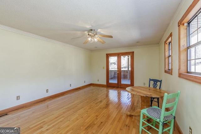 interior space with ceiling fan, light wood-type flooring, ornamental molding, and french doors