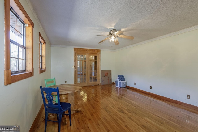 interior space with french doors, ornamental molding, a textured ceiling, ceiling fan, and wood-type flooring