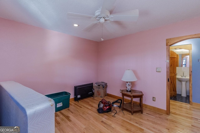 sitting room featuring ceiling fan, sink, and light wood-type flooring