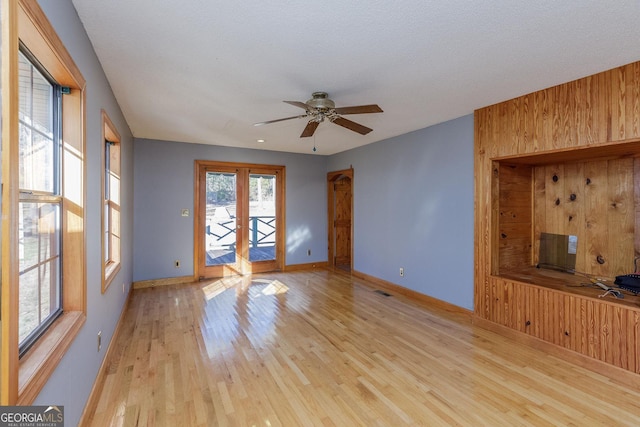 unfurnished living room featuring french doors, light hardwood / wood-style floors, and ceiling fan