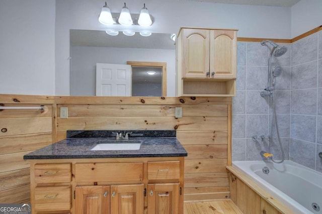 bathroom featuring hardwood / wood-style floors, tiled shower / bath, and vanity