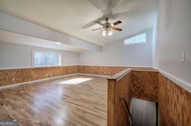 unfurnished room with ceiling fan, hardwood / wood-style floors, wood walls, and lofted ceiling