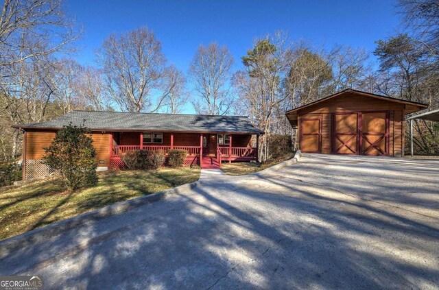 single story home with a garage, a front lawn, covered porch, and an outdoor structure