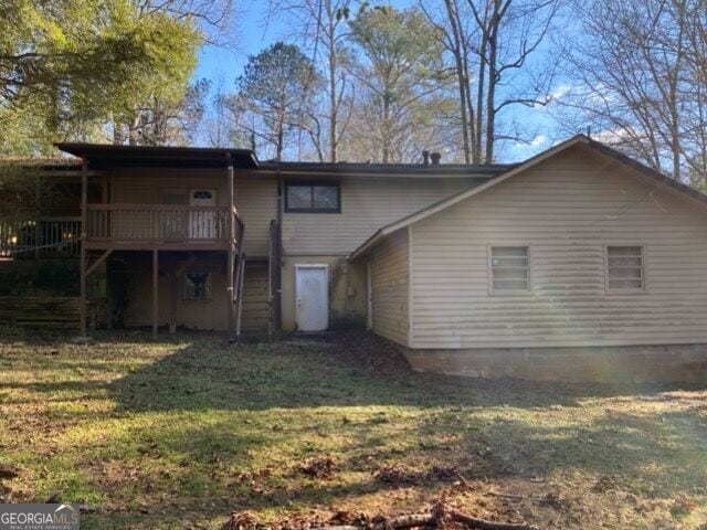 back of house featuring a lawn and a wooden deck