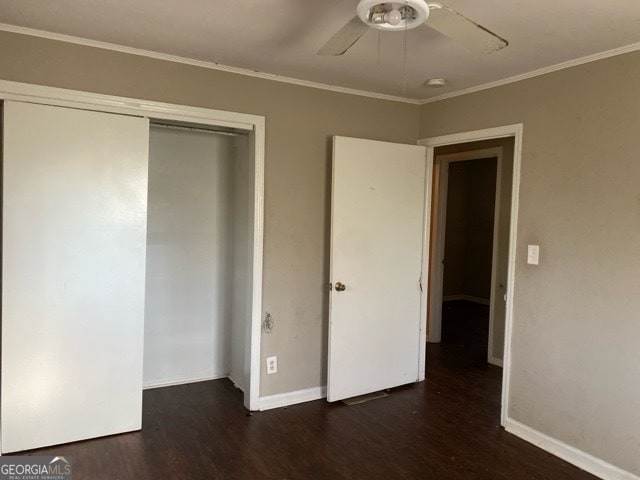 unfurnished bedroom featuring dark wood-type flooring, ceiling fan, ornamental molding, and a closet