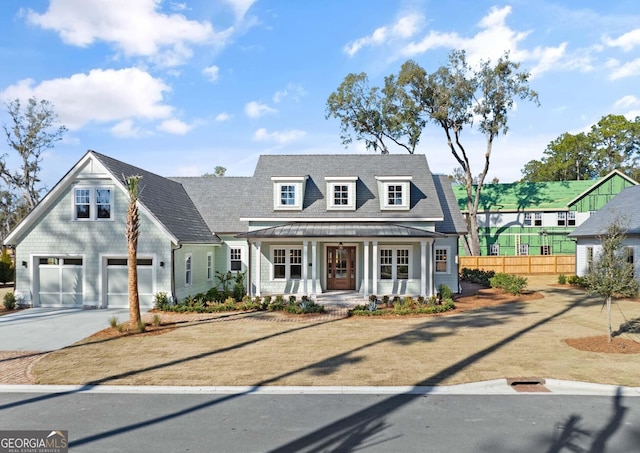 cape cod home featuring a garage and covered porch