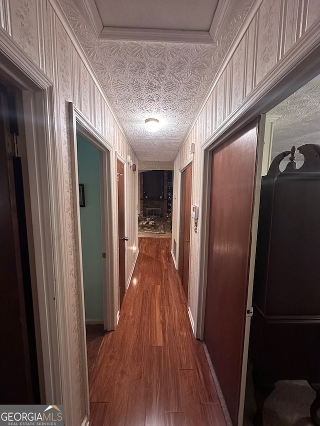 hallway featuring a textured ceiling, dark wood-type flooring, and ornamental molding