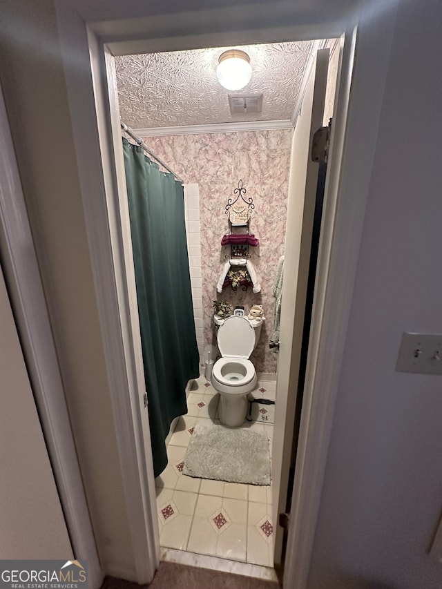 bathroom with tile floors, toilet, ornamental molding, and a textured ceiling