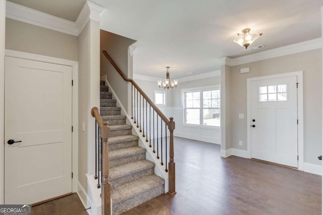 foyer entrance featuring an inviting chandelier, crown molding, and dark wood-type flooring