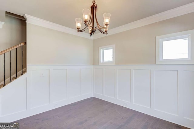 spare room featuring an inviting chandelier, crown molding, and dark hardwood / wood-style floors