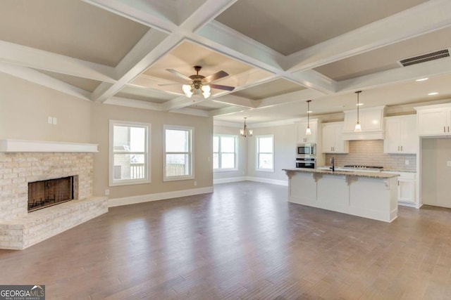 kitchen with beam ceiling, coffered ceiling, stainless steel appliances, and hardwood / wood-style flooring