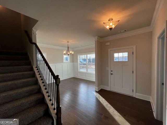 entryway with dark hardwood / wood-style flooring, crown molding, and a notable chandelier