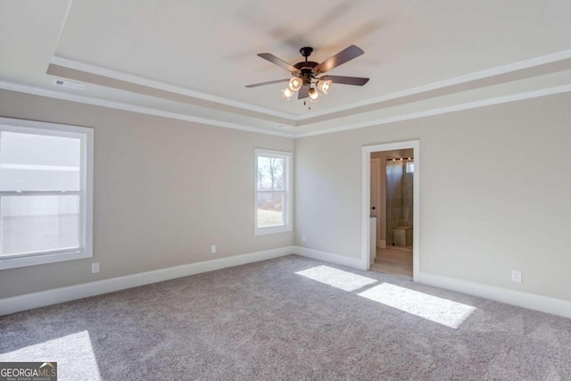 unfurnished room with ceiling fan, a raised ceiling, ornamental molding, and light colored carpet