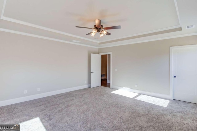 carpeted spare room with crown molding, ceiling fan, and a tray ceiling