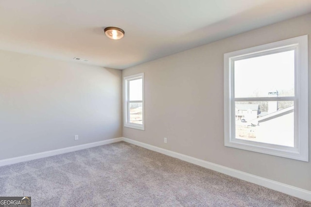 spare room featuring a wealth of natural light and light colored carpet