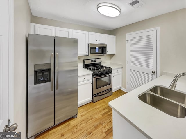 kitchen featuring sink, white cabinets, stainless steel appliances, and light hardwood / wood-style flooring