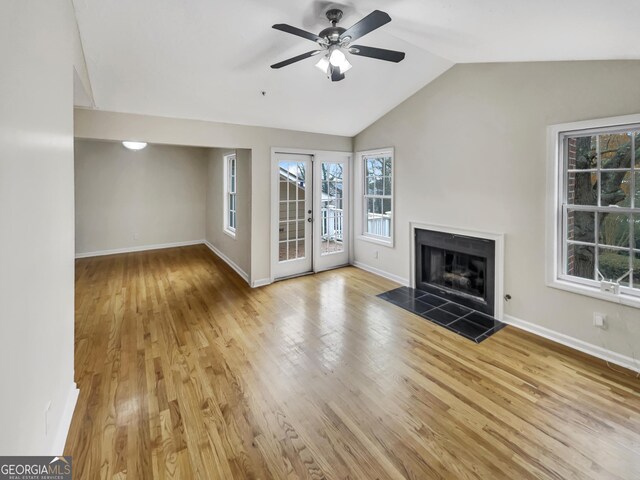 unfurnished living room featuring a tiled fireplace, ceiling fan, vaulted ceiling, and light wood-type flooring