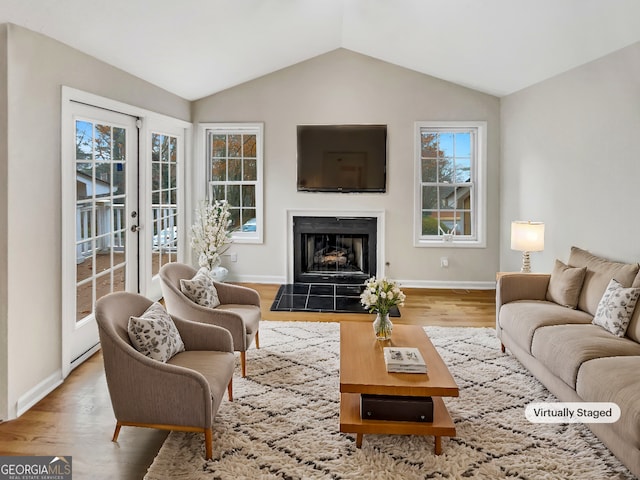 living room with hardwood / wood-style flooring, vaulted ceiling, and a tiled fireplace