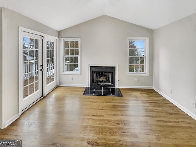 unfurnished living room with vaulted ceiling, a healthy amount of sunlight, and light hardwood / wood-style flooring