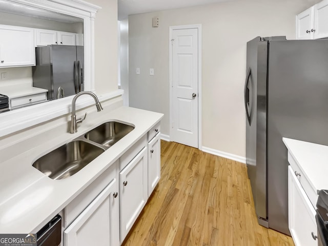 kitchen featuring white cabinets, light hardwood / wood-style flooring, stainless steel refrigerator, and sink