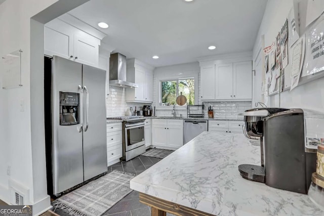 kitchen featuring wall chimney range hood, white cabinetry, dark tile floors, and appliances with stainless steel finishes