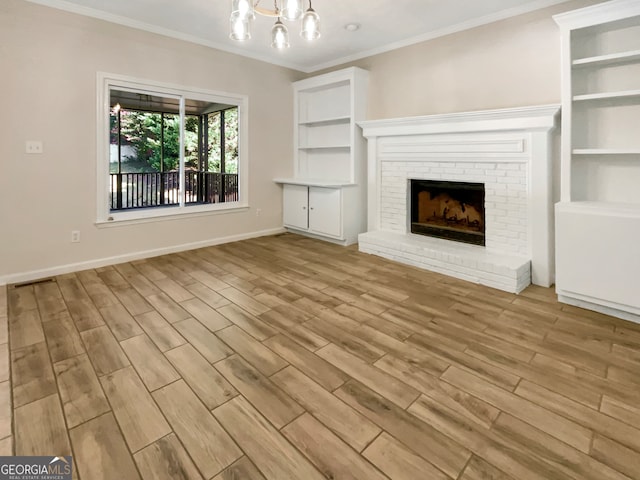 unfurnished living room with a fireplace, light hardwood / wood-style floors, an inviting chandelier, and crown molding