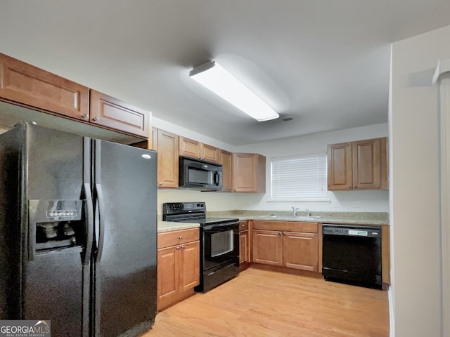 kitchen with sink, light hardwood / wood-style floors, and black appliances