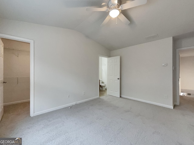 unfurnished bedroom featuring a walk in closet, light colored carpet, ceiling fan, a closet, and lofted ceiling