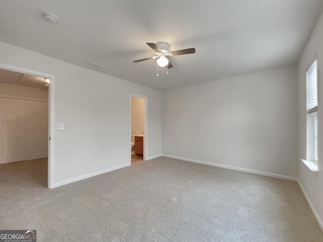 unfurnished bedroom featuring a walk in closet, light colored carpet, ceiling fan, connected bathroom, and a closet