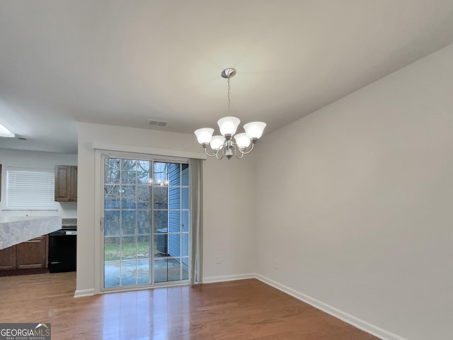 unfurnished dining area featuring light wood-type flooring and an inviting chandelier