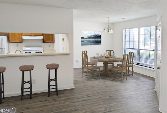 kitchen with a kitchen bar, pendant lighting, white appliances, and a notable chandelier