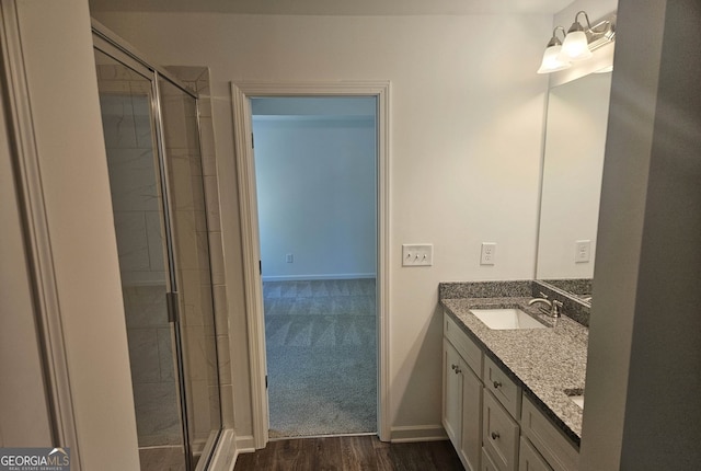 bathroom with an enclosed shower, wood-type flooring, dual sinks, and vanity with extensive cabinet space