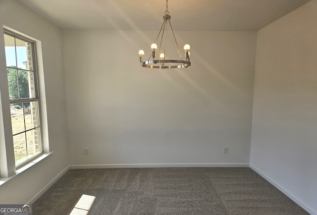 carpeted empty room with an inviting chandelier