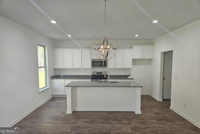 kitchen with stove, a center island with sink, white cabinetry, and dark wood-type flooring