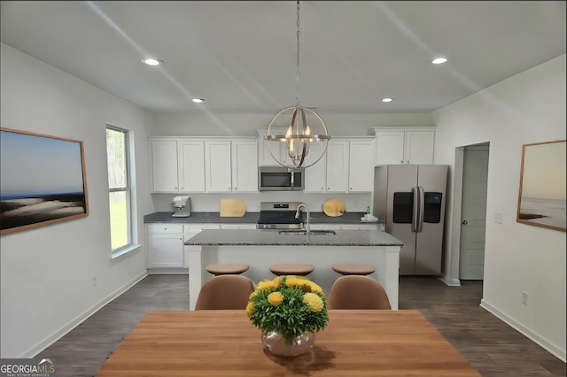 kitchen featuring appliances with stainless steel finishes, white cabinetry, an island with sink, and dark hardwood / wood-style flooring