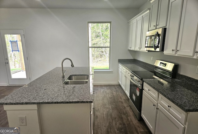 kitchen with a center island with sink, appliances with stainless steel finishes, sink, and dark wood-type flooring