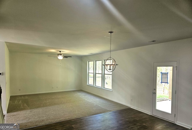 unfurnished room with a healthy amount of sunlight, dark hardwood / wood-style floors, and ceiling fan with notable chandelier