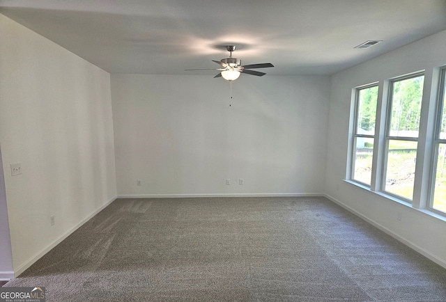 spare room with a wealth of natural light, ceiling fan, and dark carpet