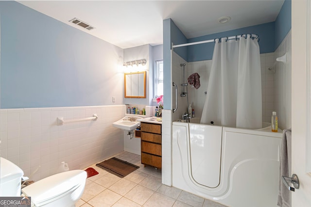 bathroom featuring sink, tile floors, toilet, and tile walls