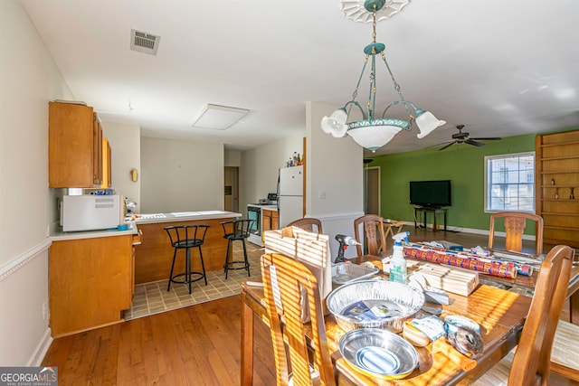 dining space with ceiling fan and light wood-type flooring