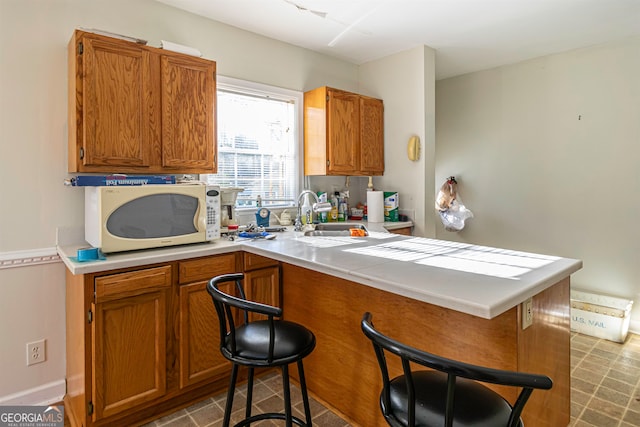 kitchen with a breakfast bar area, light tile flooring, and sink