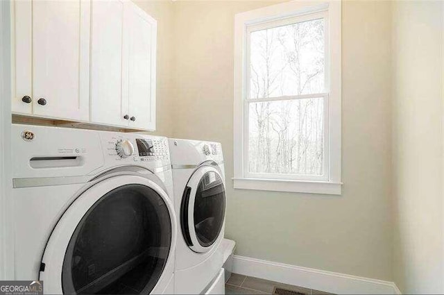 laundry area featuring plenty of natural light, cabinets, washer and dryer, and tile flooring