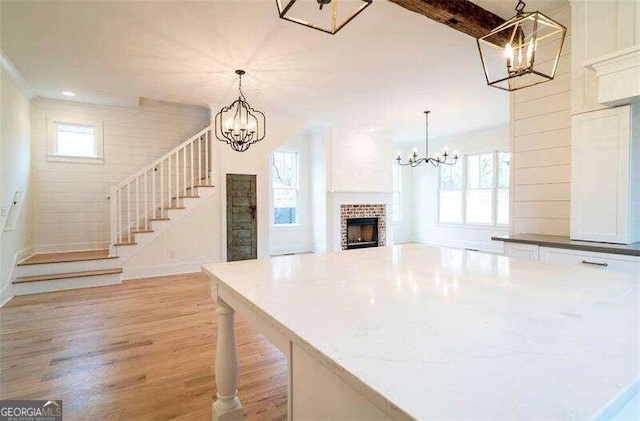 kitchen featuring a fireplace, white cabinetry, a chandelier, and light hardwood / wood-style floors