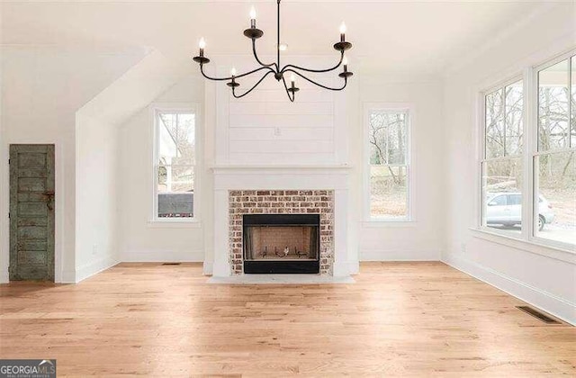 unfurnished living room featuring light wood-type flooring, plenty of natural light, and a chandelier