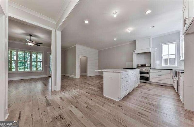 kitchen featuring ceiling fan, crown molding, double oven range, white cabinetry, and light wood-type flooring