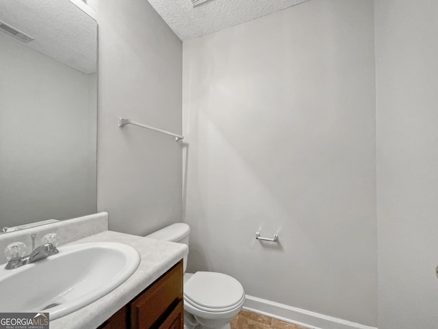 bathroom featuring vanity, a textured ceiling, and toilet