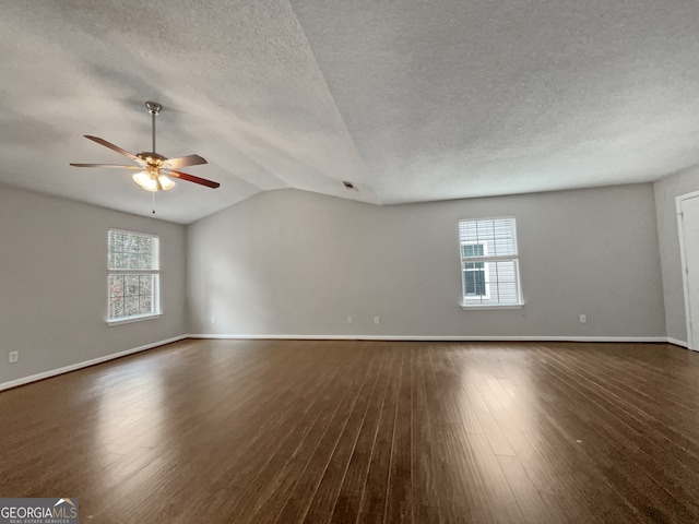 unfurnished room featuring vaulted ceiling, a textured ceiling, dark hardwood / wood-style flooring, and ceiling fan